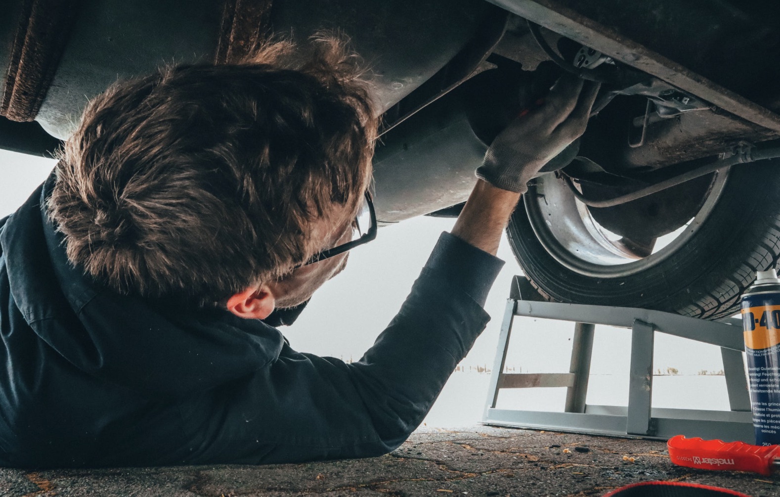 Volkswagen being repaired with a man underneath the vehicle.