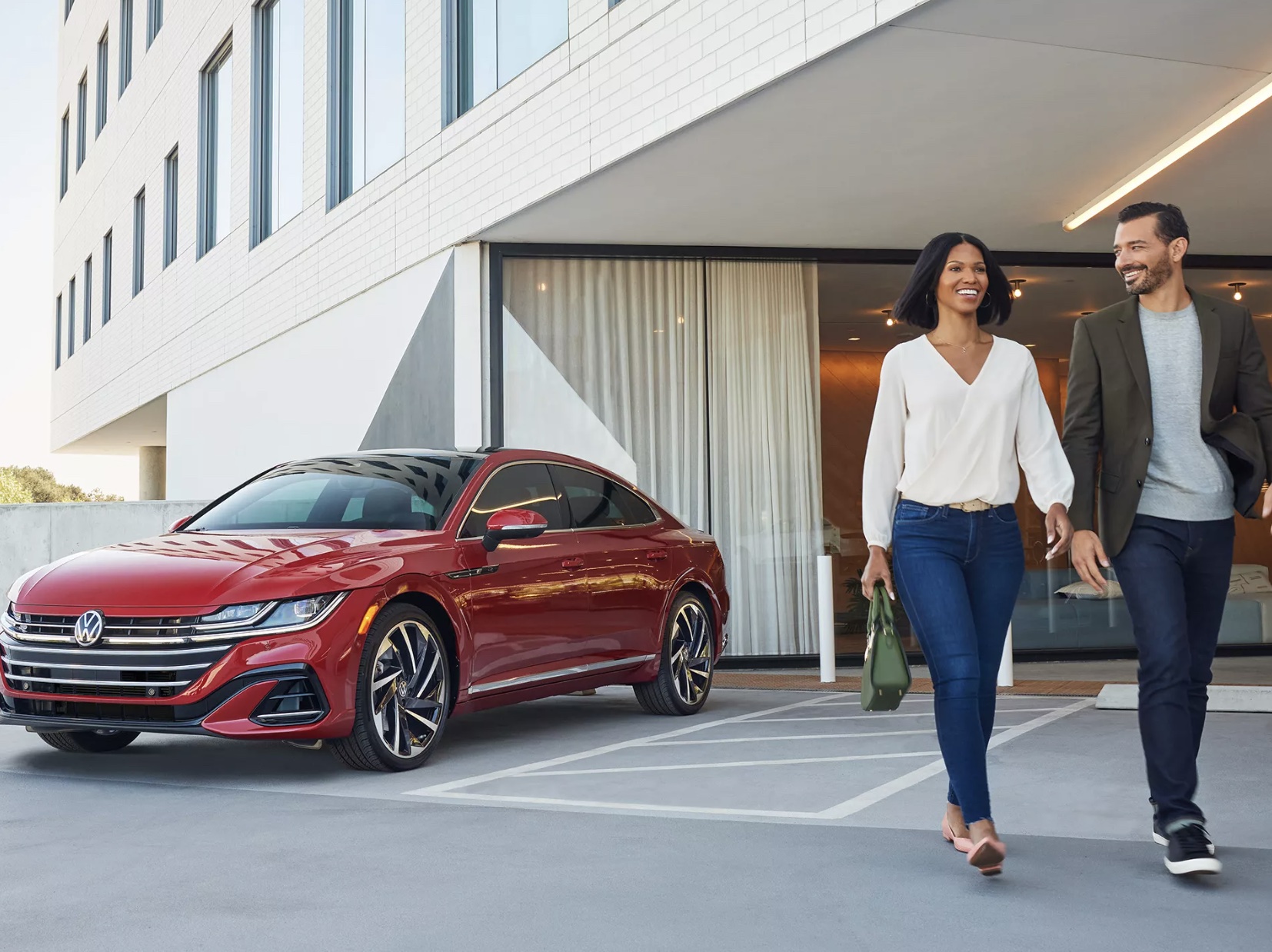 A couple walking away from their VW Arteon in Elign, IL purchased from a lineup of Used Volkswagen Models