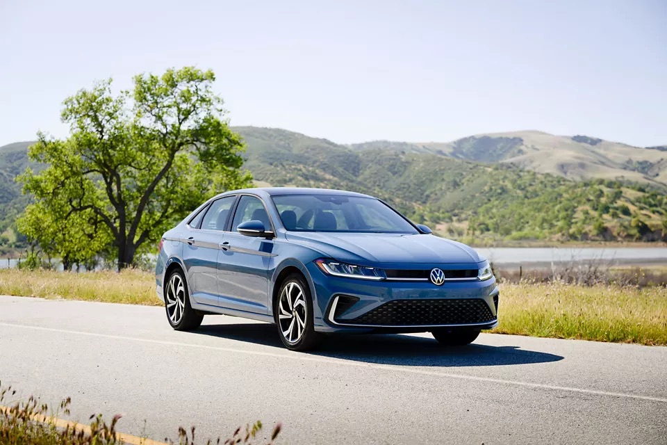 A blue 2025 Volkswagen Jetta driving on a road in Rockford, IL.